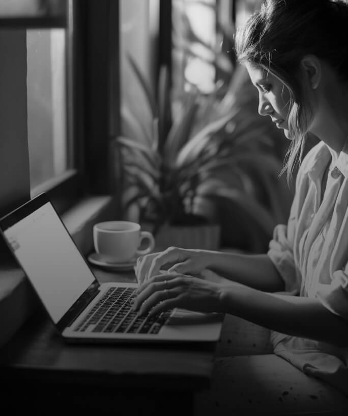 Person working on laptop with coffee cup