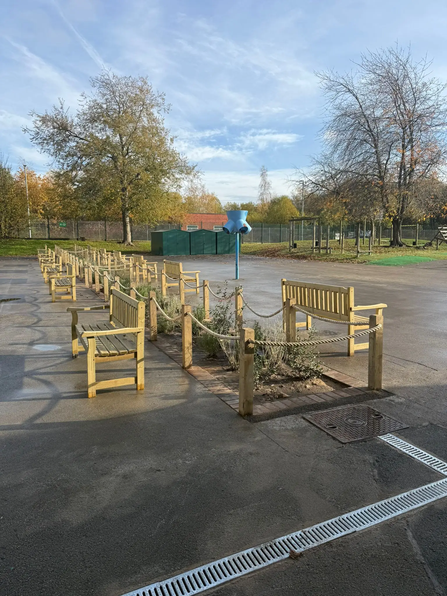 Several wooden crates are arranged in an outdoor area with trees and a blue structure in the background.