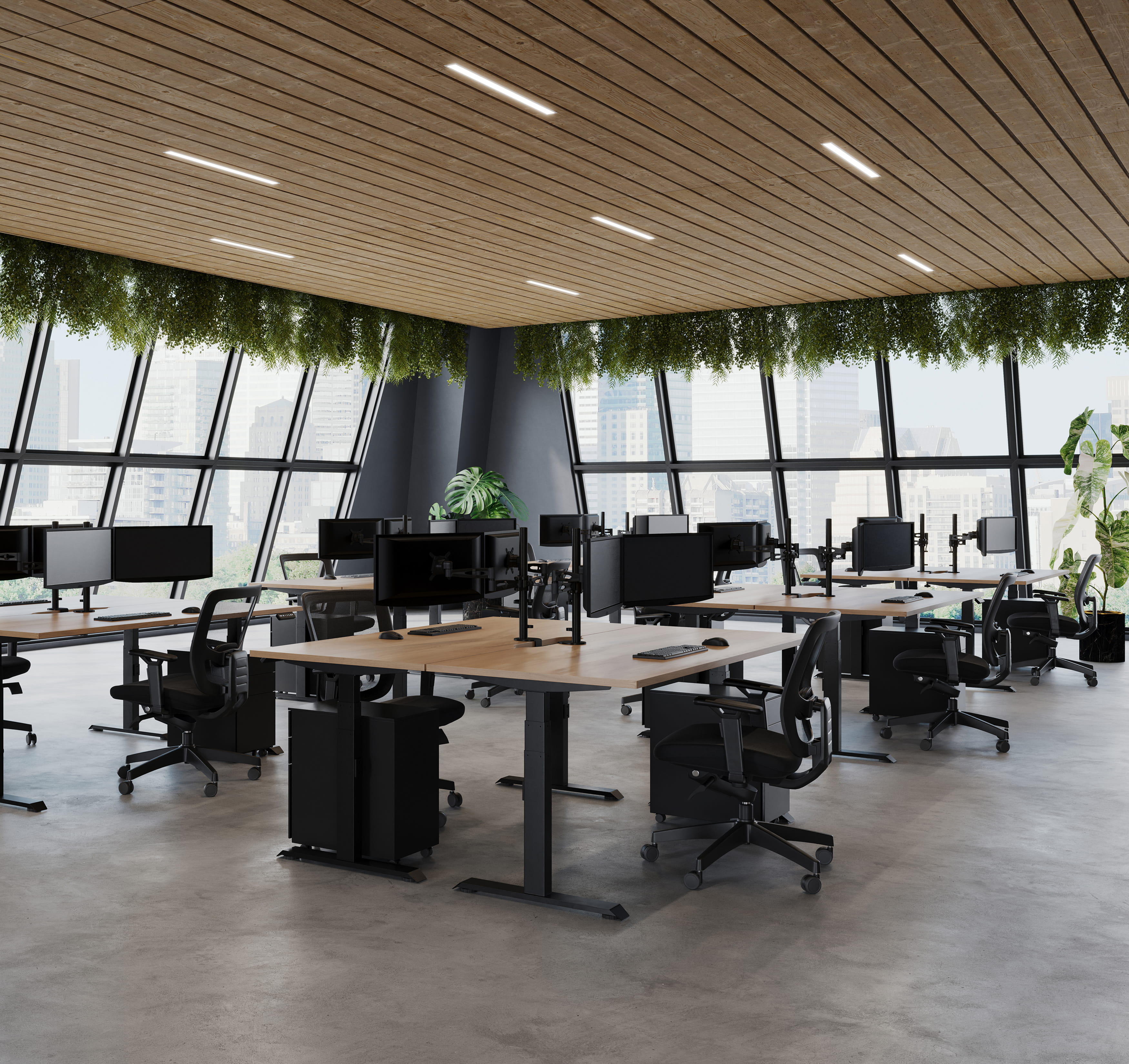 Open office layout with multiple desks, monitors, and natural light from large windows