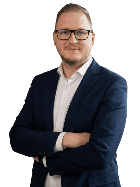 A well-dressed individual in a blue blazer poses confidently with a slight smile against a neutral background.