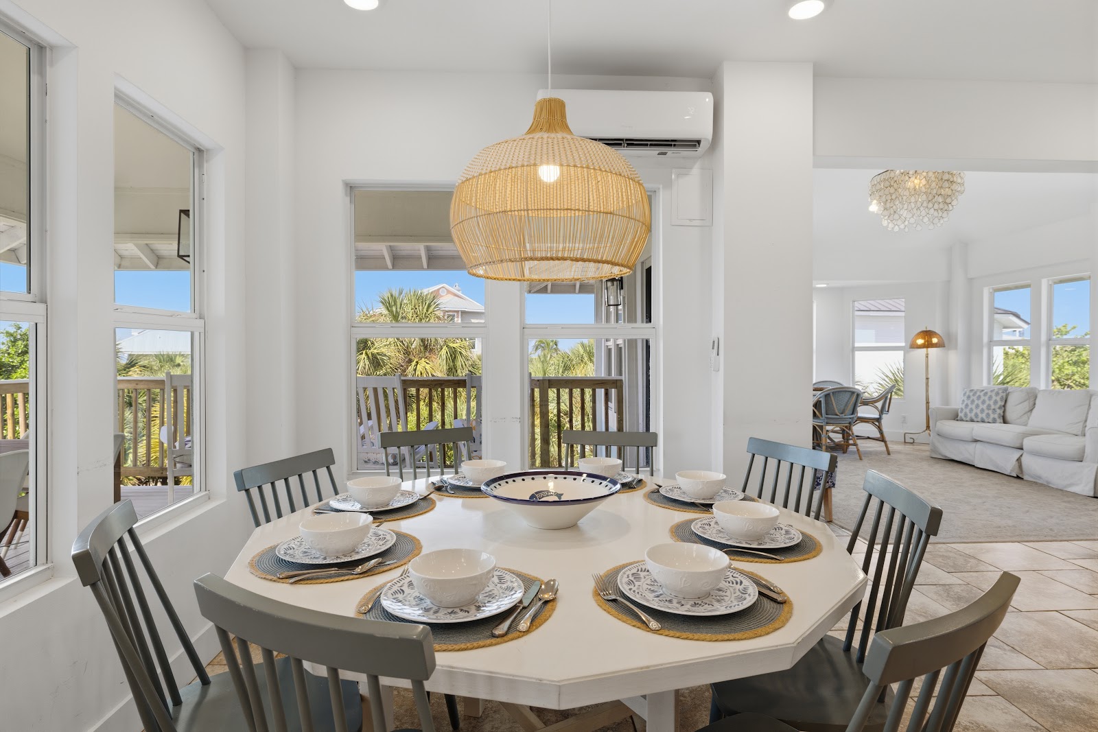 Dining table and living room beyond, under a woven pendant