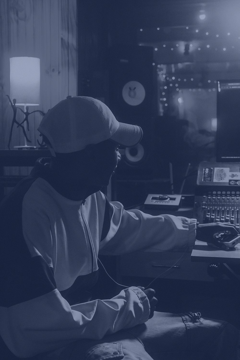 Person sitting on the ground wearing a suit made of dollar bills, surreal blue background, creative studio artwork.