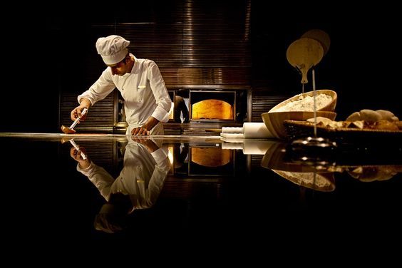 Chef preparing a dish in a wood fired kitchen, symbolizing the craftsmanship, discipline, and culinary standards that inspire Sajid Rayani’s vision for Dhoom.
