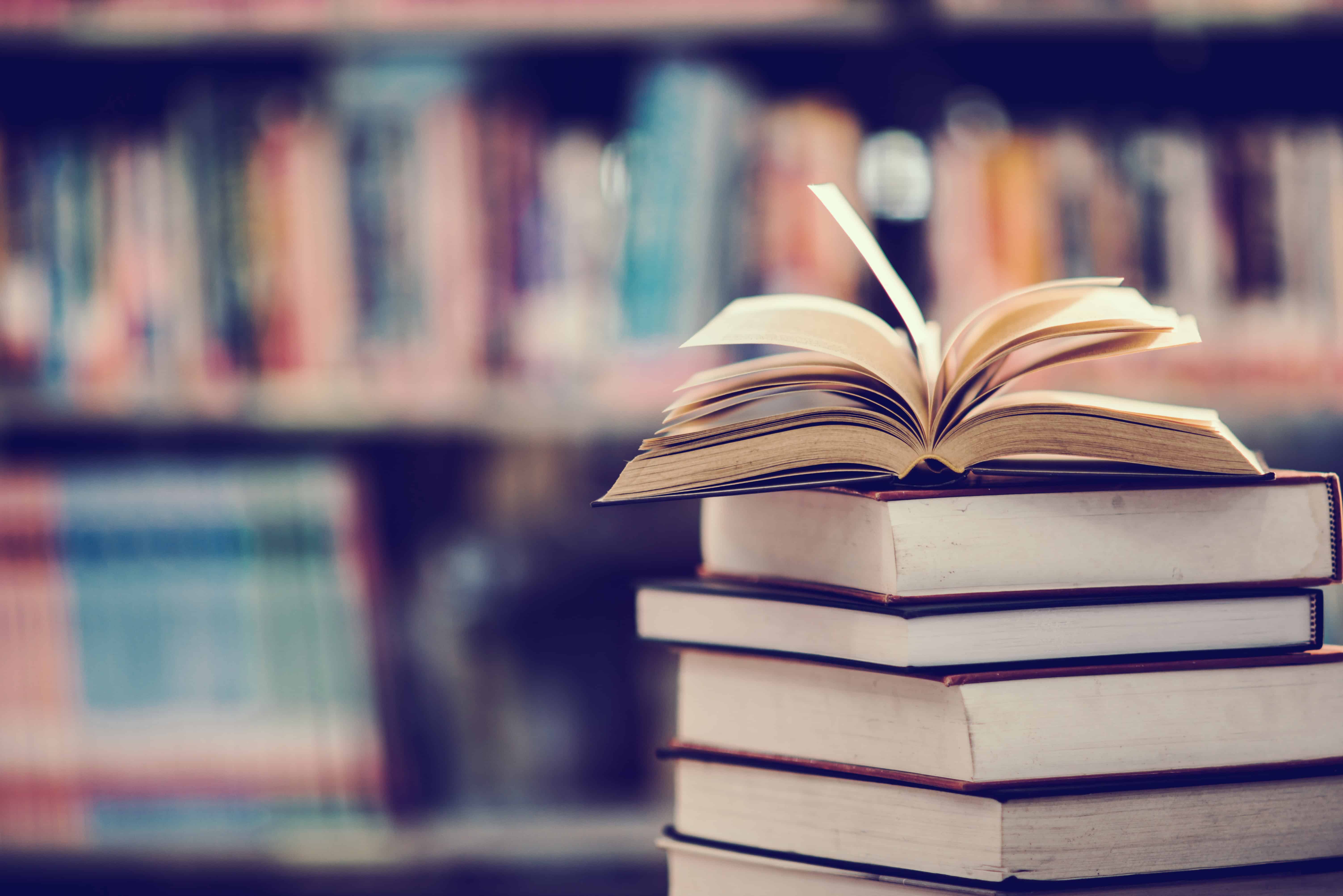 Livres scientifiques empilés avec un livre ouvert en bibliothèque, symbolisant les références et publications citées