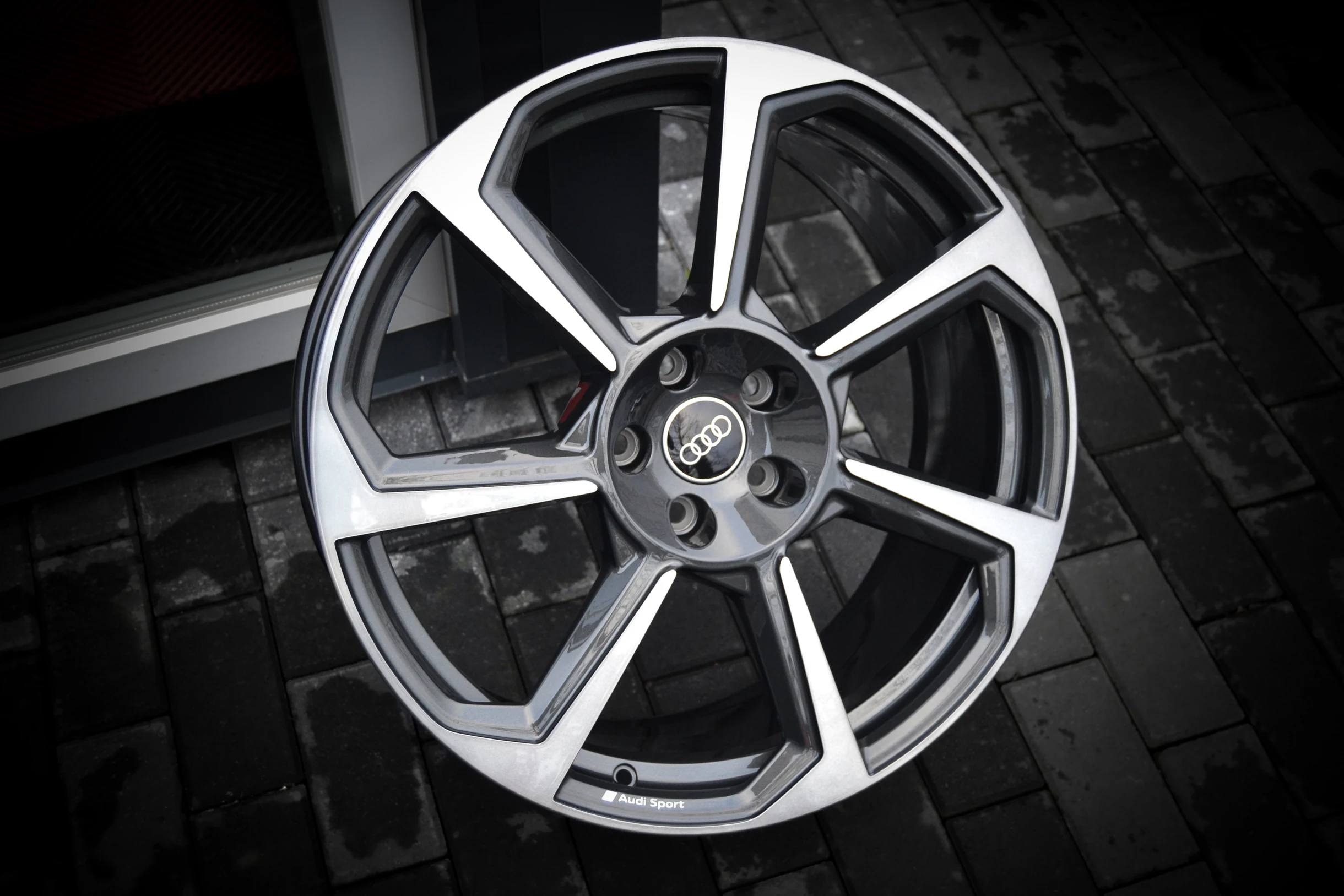 Audi-Felge mit breiten, glanzgedrehten Speichenflächen und dunklen Zwischenräumen bei AT Plus.