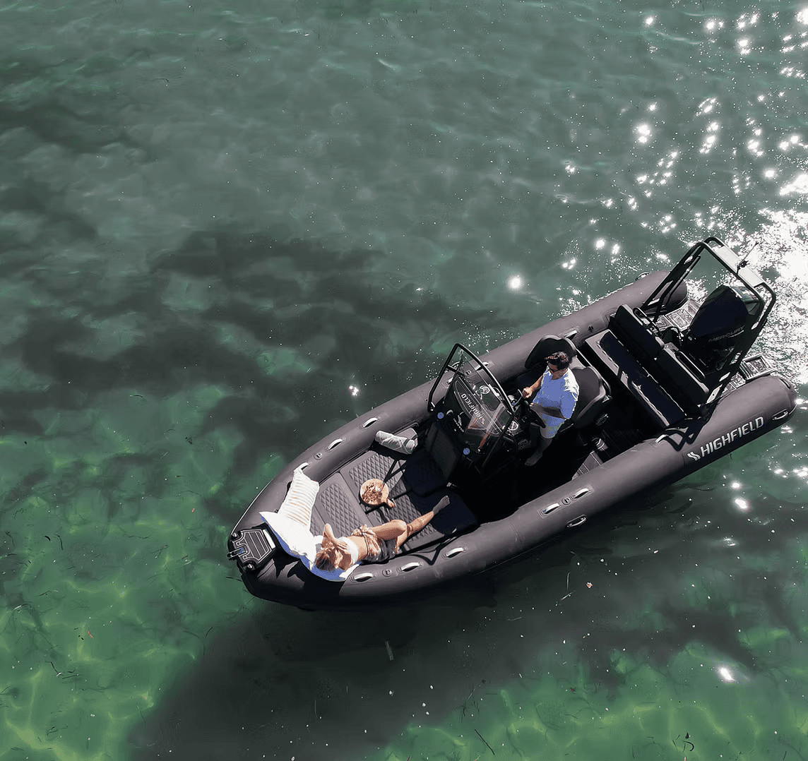 A winding road cuts through rocky terrain, surrounded by patches of green grass and illuminated by sunlight.