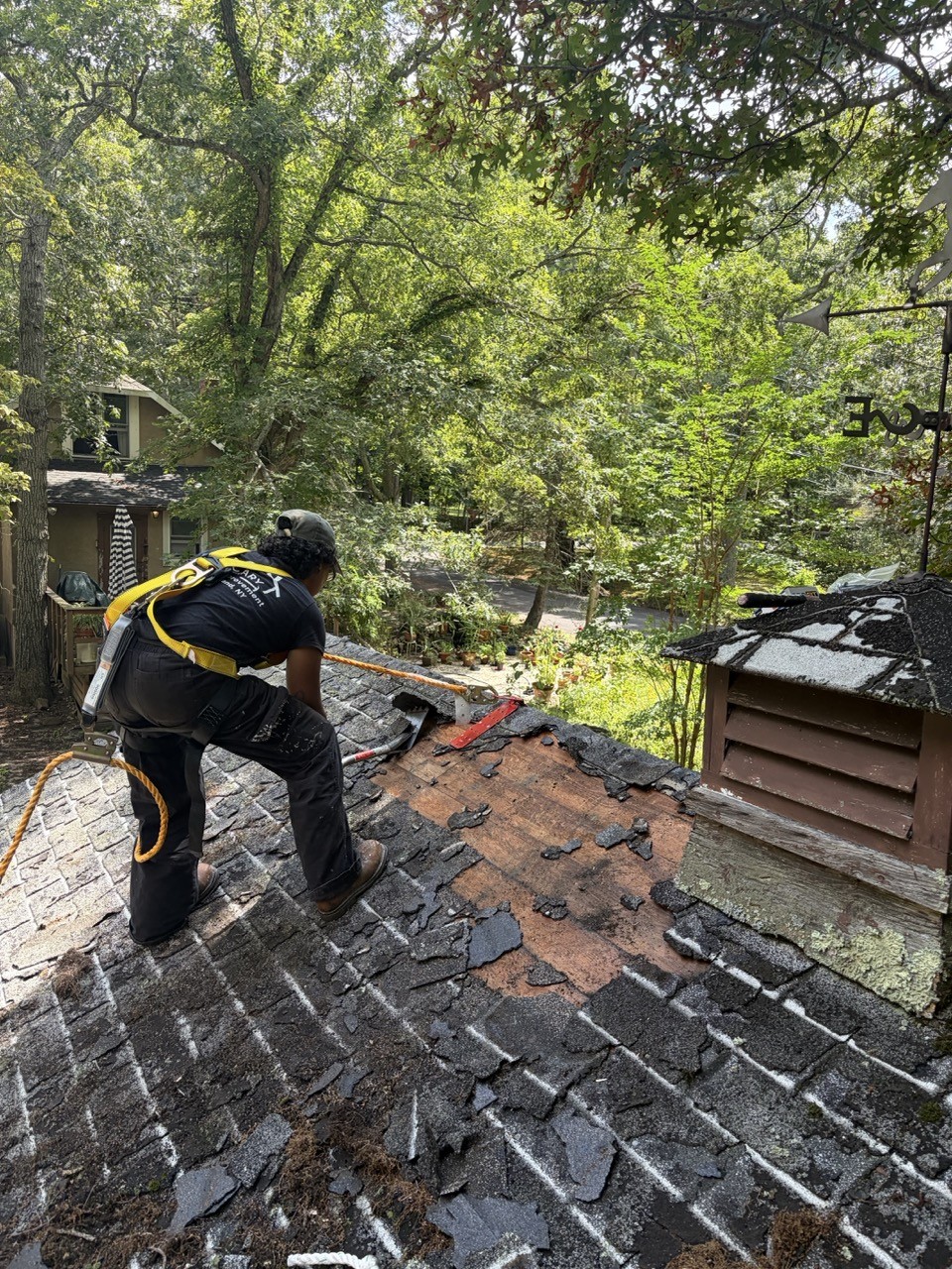 Crew member stripping the old shingles off during the roof tear-off