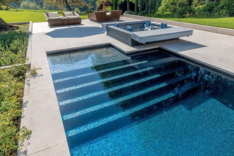 Breite Treppenanlage ins Becken mit blauem Glasmosaik und integriertem Spa