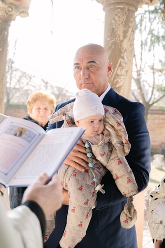 Nasul care tine bebelusul in brate la slujba de botez