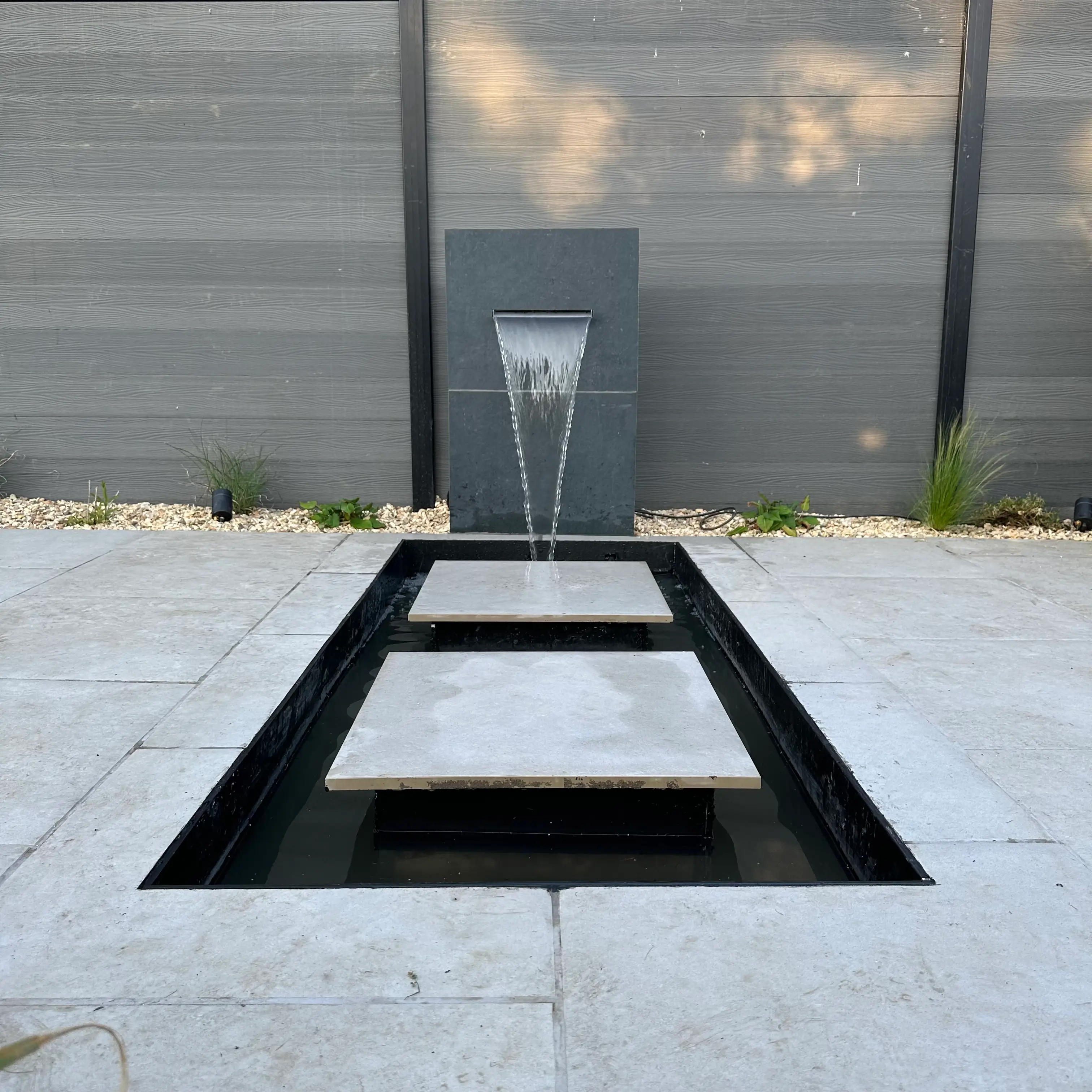 A modern minimalist entrance with a sleek black frame and concrete flooring under a cloudy sky.