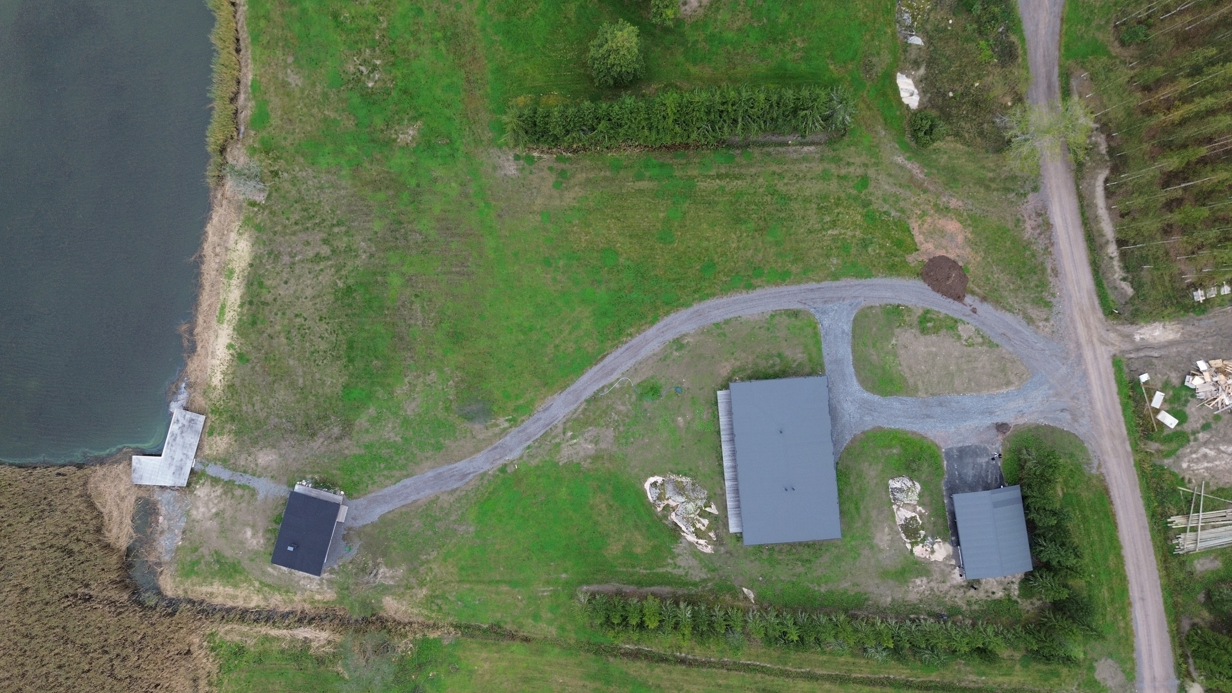 Aerial view of the yard, which has a sauna building, a house, and a carport.