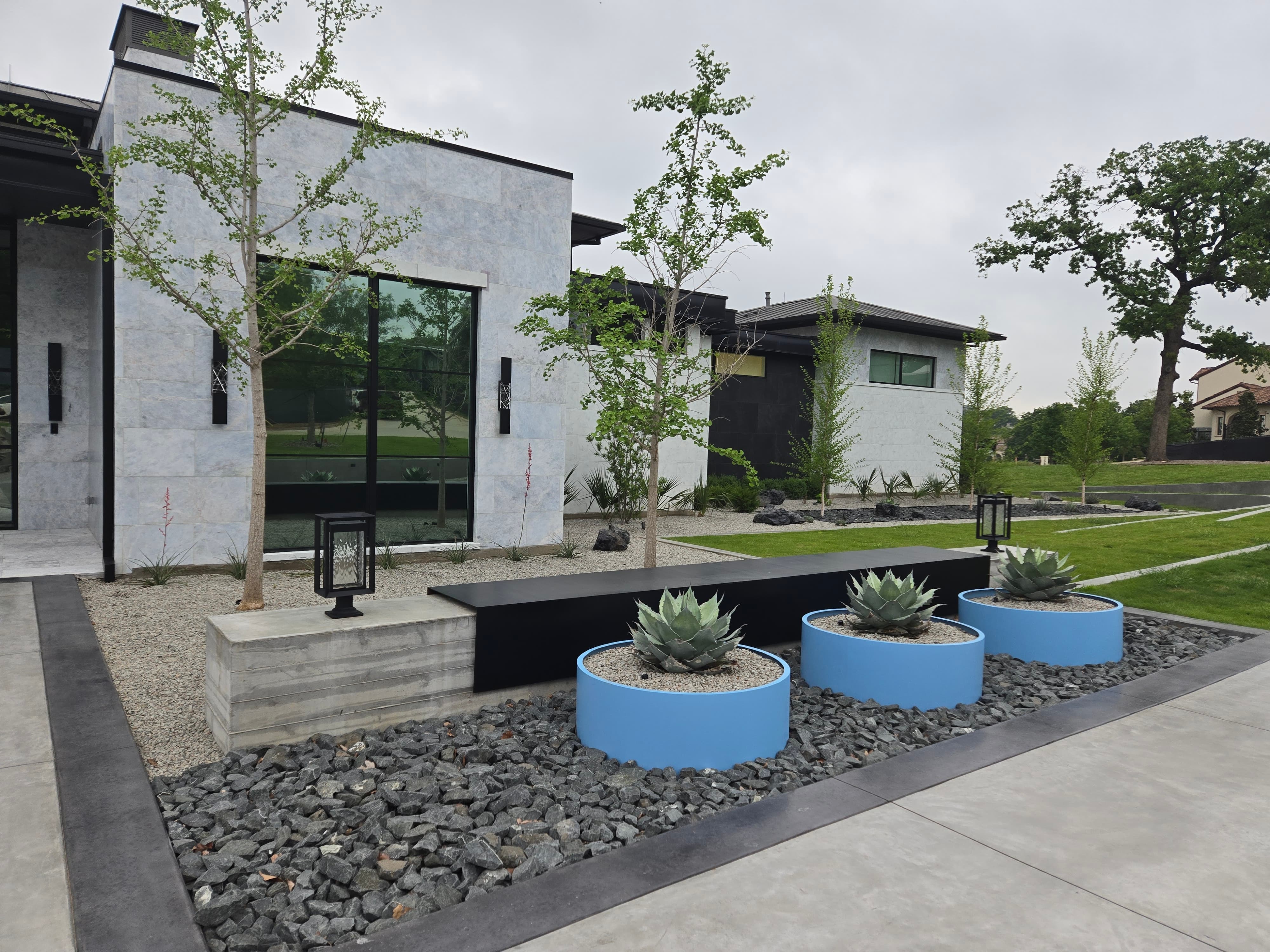 Modern front entry with flush concrete bands, integrated planter beds, and a low-profile path lantern