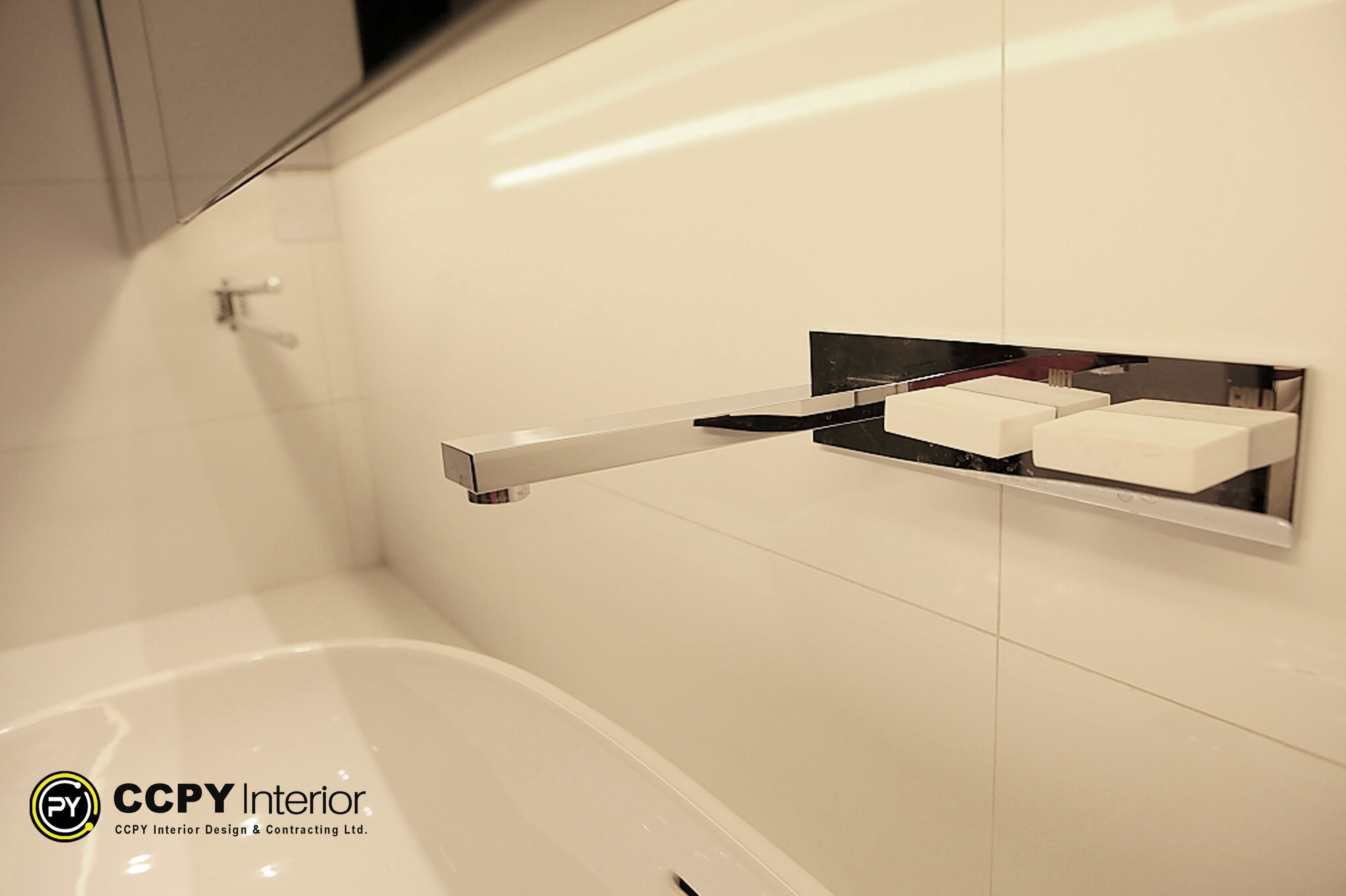 Sleek wall-mounted chrome bathroom faucet with modern square levers over a white basin in Standalone House, Perkins Road.