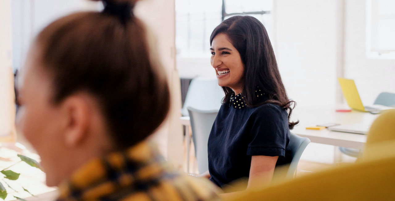 Workshop participant smiling during a UX design team discussion in a bright modern office