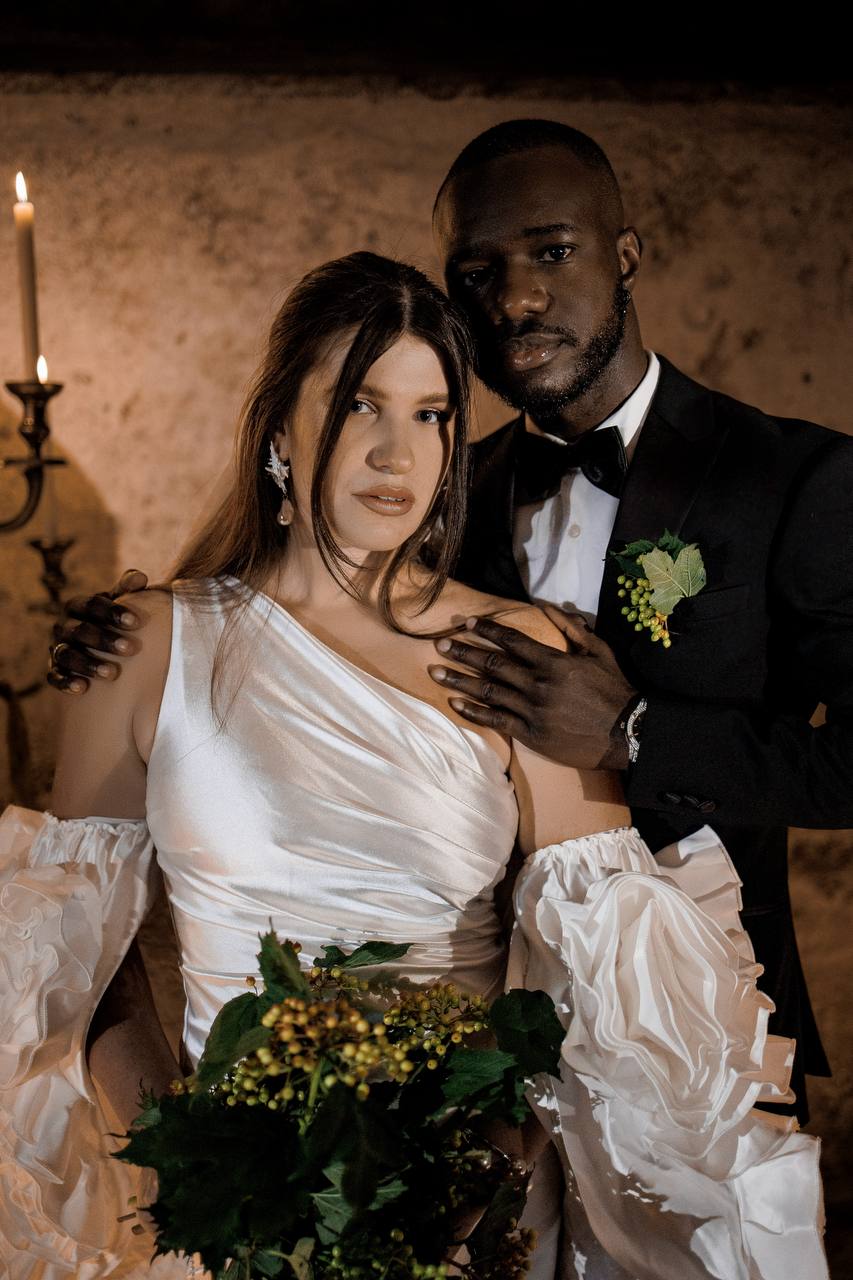 Close-up of a bride in an elegant white wedding dress surrounded by candles