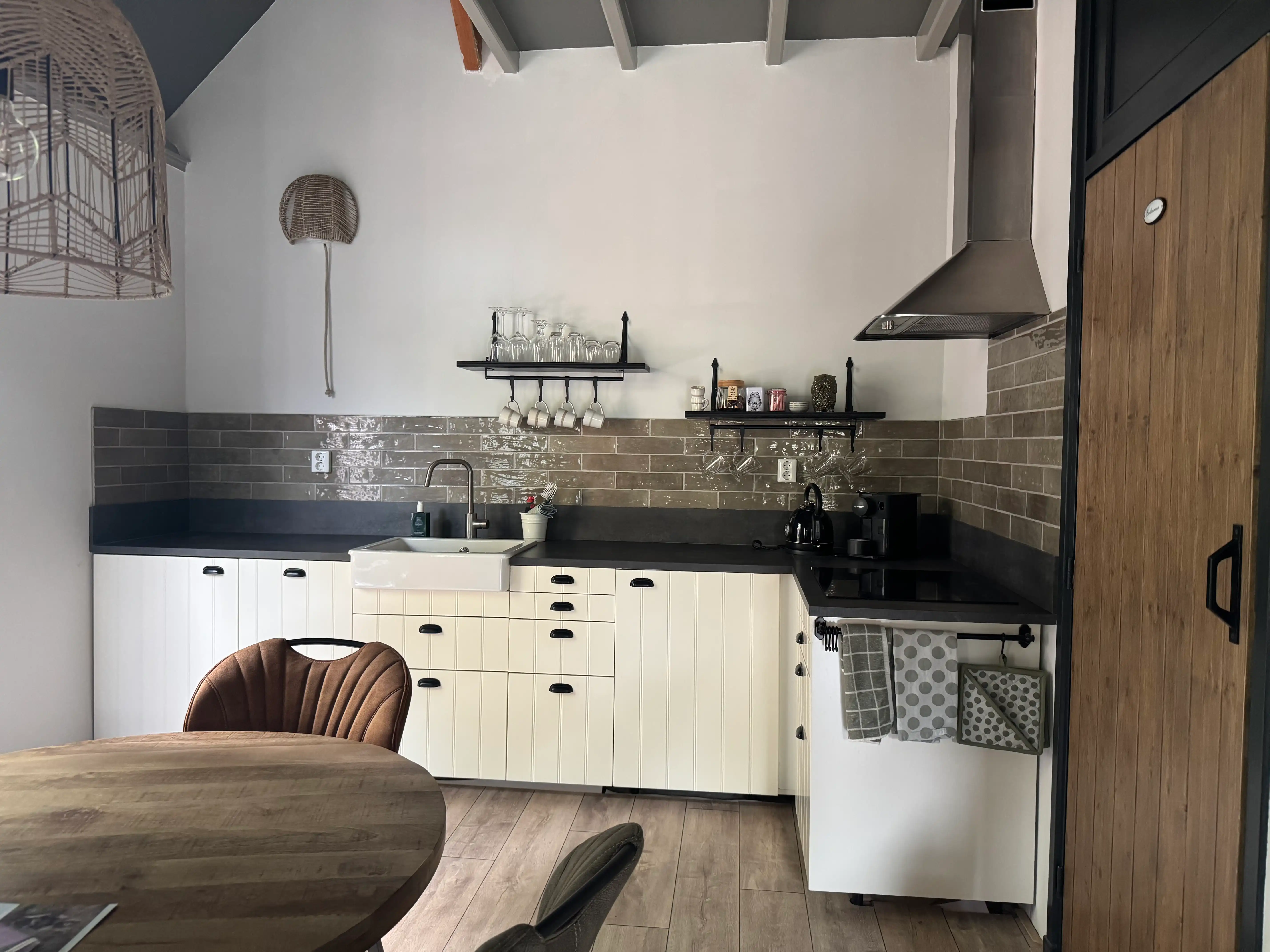 Landelijke witte keuken met houtlook achterwand en moderne apparatuur.