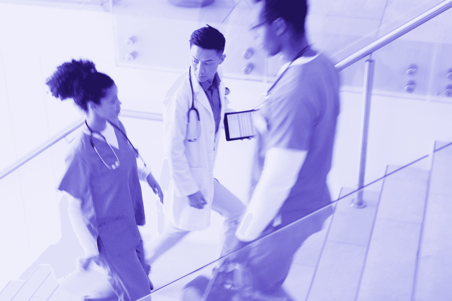 Imagem, em tons de roxo, de três profissionais da saúde caminhando em uma escada de um hospital.