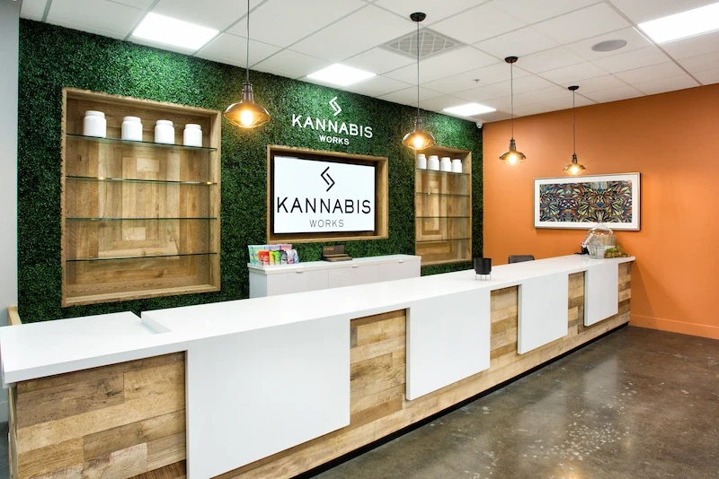 Modern checkout area with green tile, wooden trim, and orange walls at Kannabis Works.