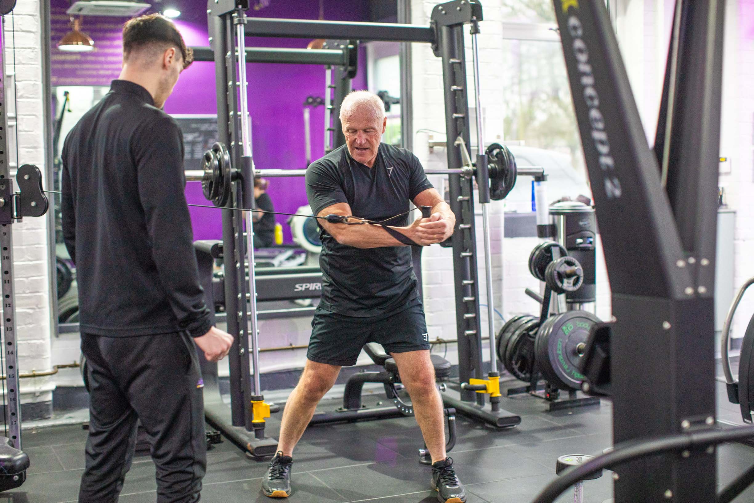 A man works out in a gym, showcasing strength for his New Year fitness resolutions, by Alchemy.