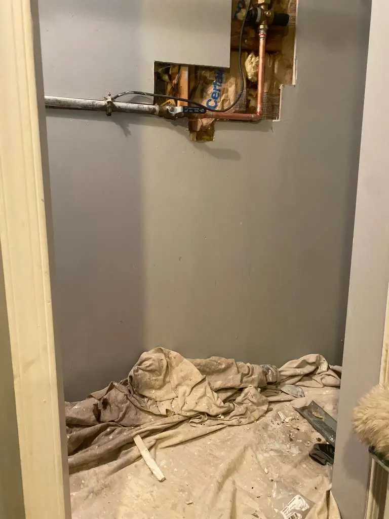 A precise section of drywall removed to expose hidden copper pipes, located by our professional water leak detection services.