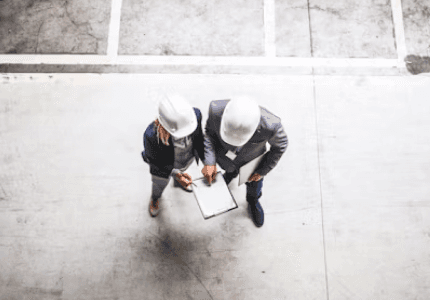 two people in hard hats looking over paper work