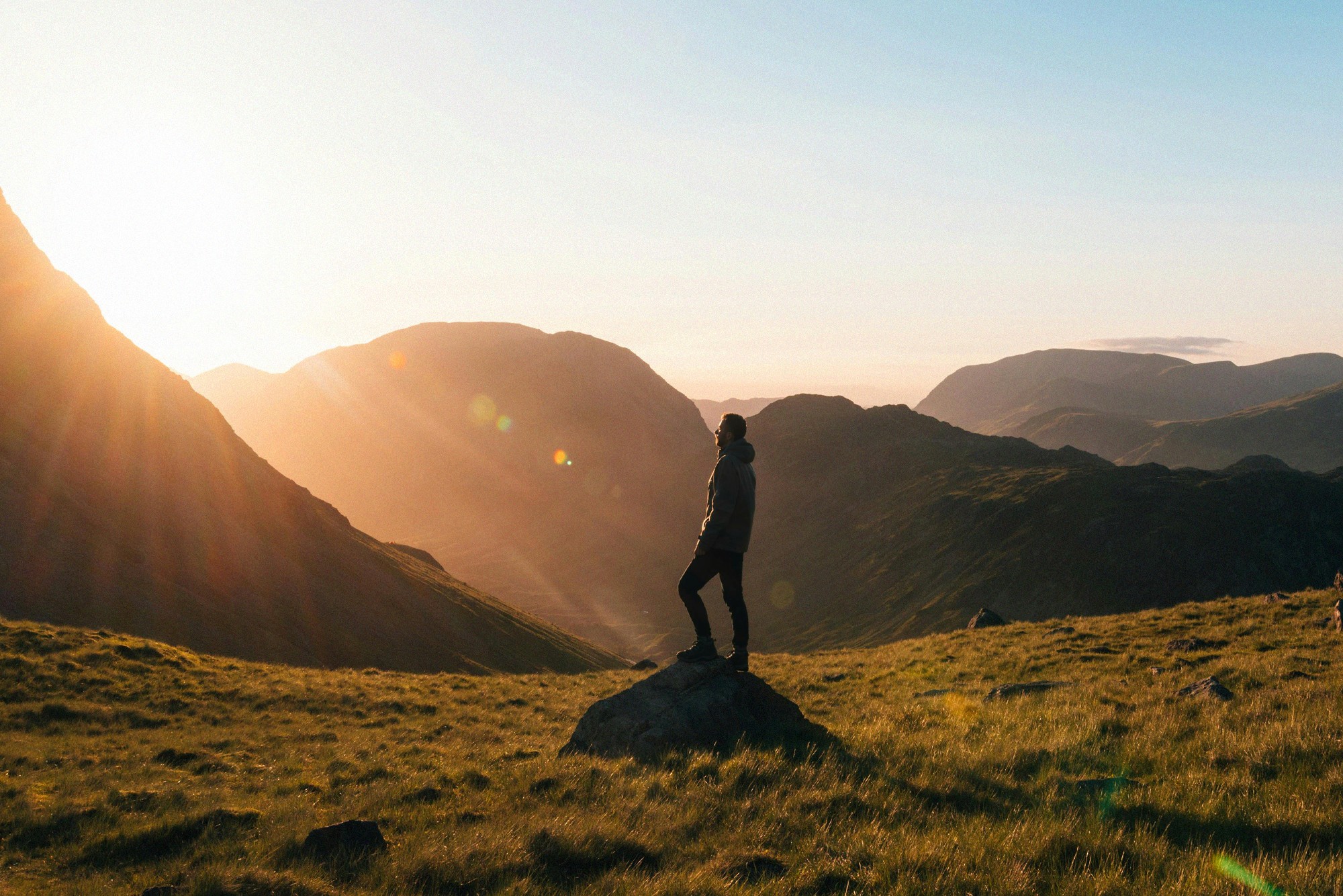 Man standing on mountain at sunrise representing clear guidance when choosing private health insurance