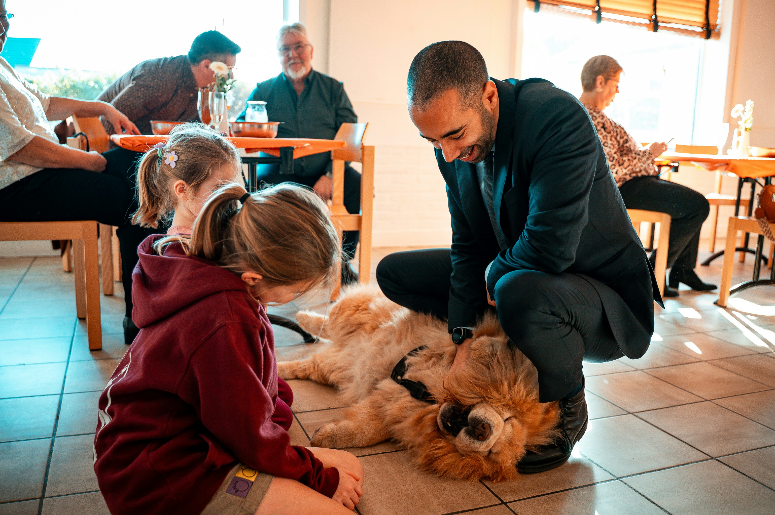 Man pets a fluffy dog with a child watching