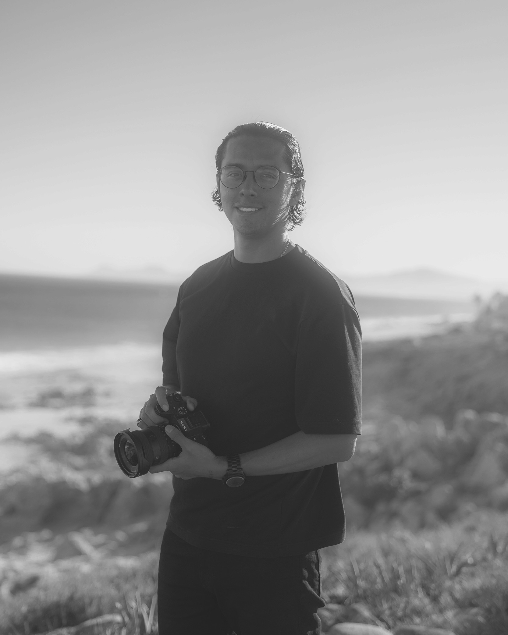 grayscale photo of person wearing black watch and black mirrorles camera