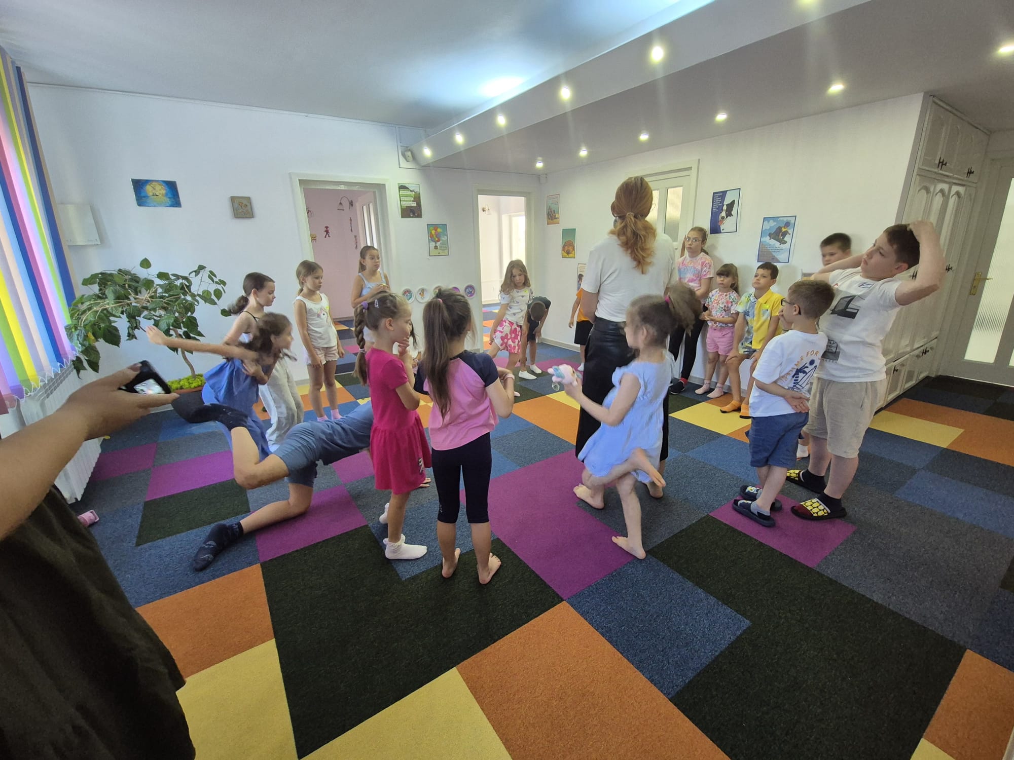 A smiling young man with crossed arms, wearing a plaid shirt and white t-shirt, poses against a dark background.