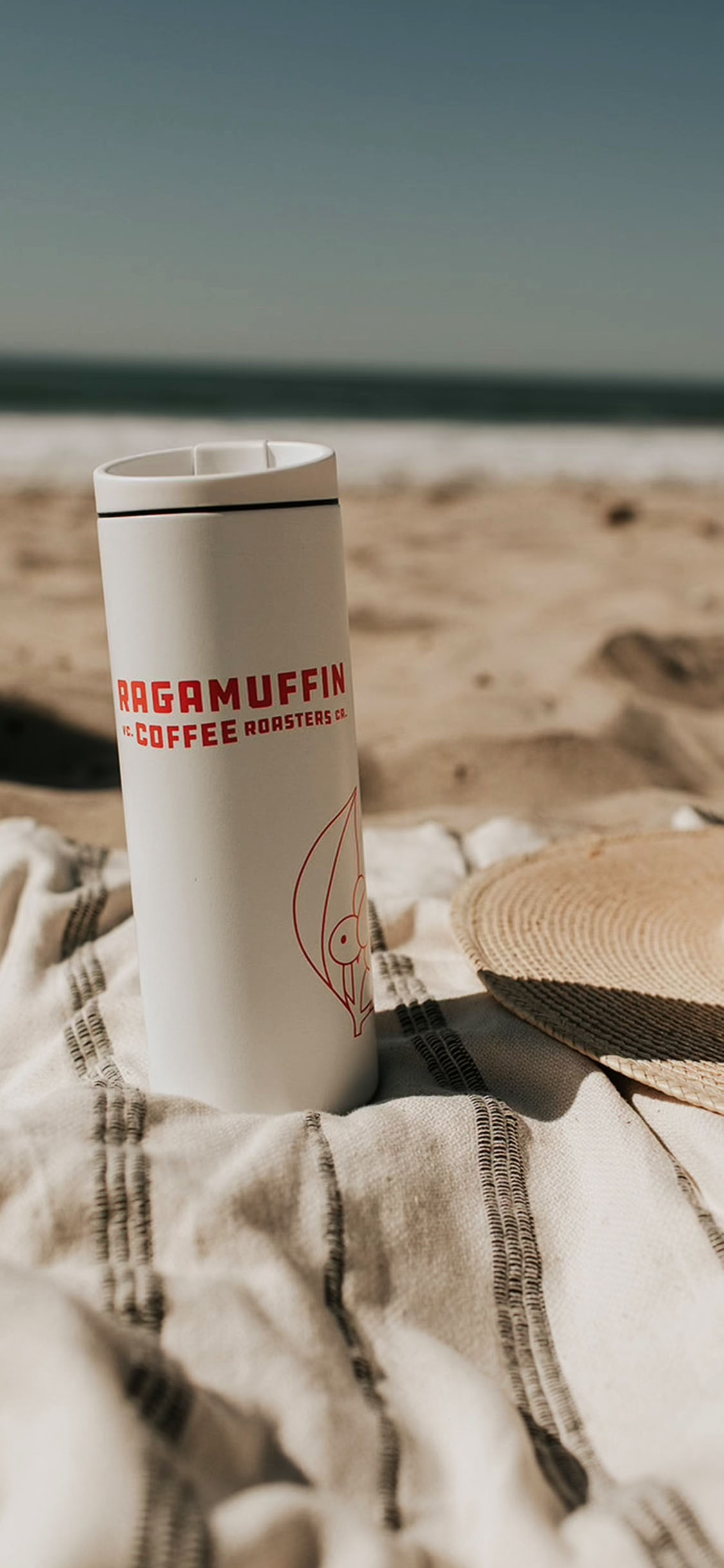 Ragamuffin branded to-go coffee cup on warm background