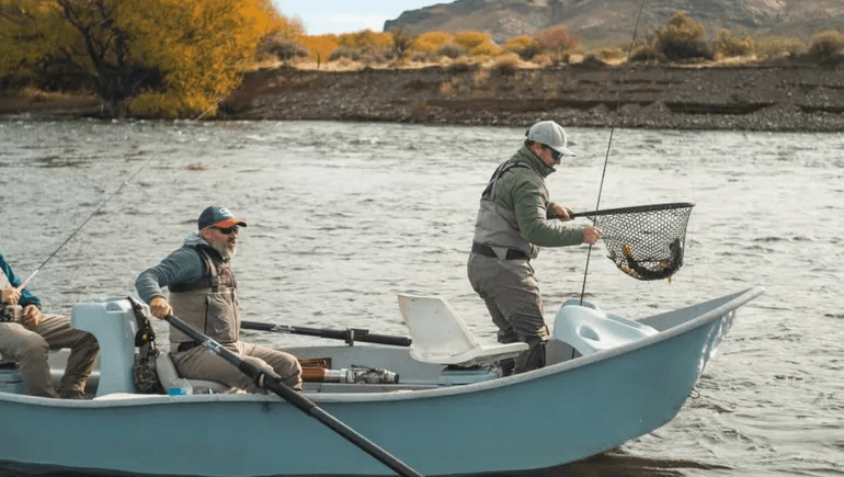 Pescadores en bote con una trucha recién capturada en su red