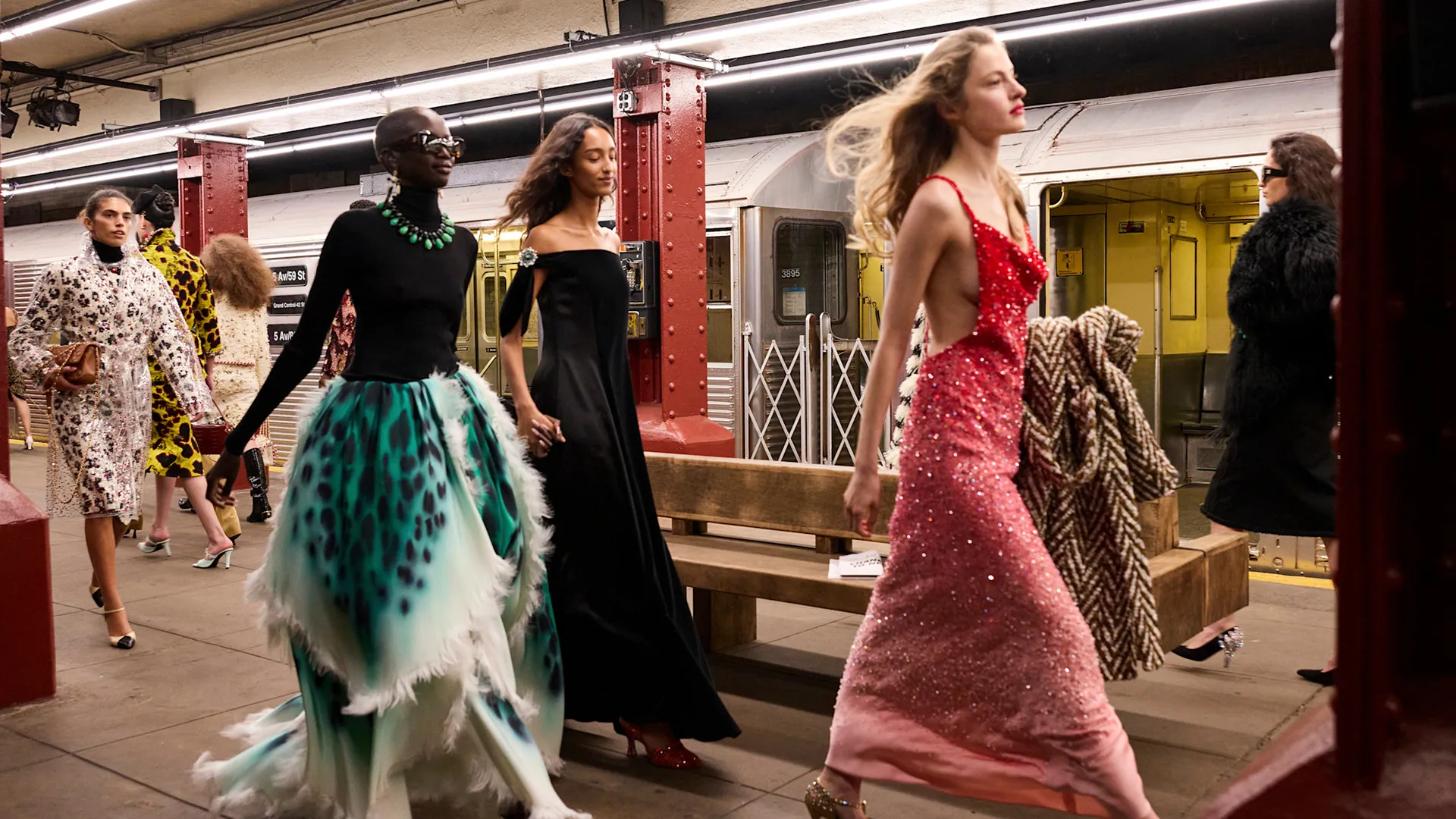 Models walk confidently through a subway platform wearing elegant gowns and layered looks during the Chanel Métiers d’Art 2026 show.