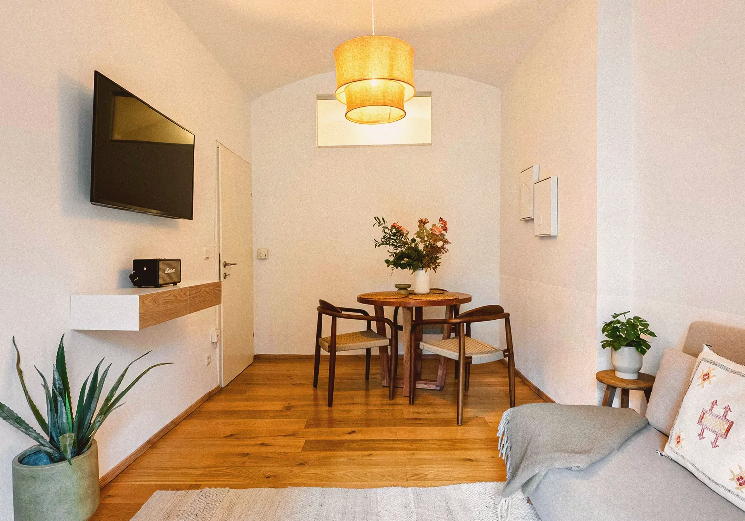 Garden N°1 • living room with a wall-mounted TV, a dining corner and a yellow pendant lamp
