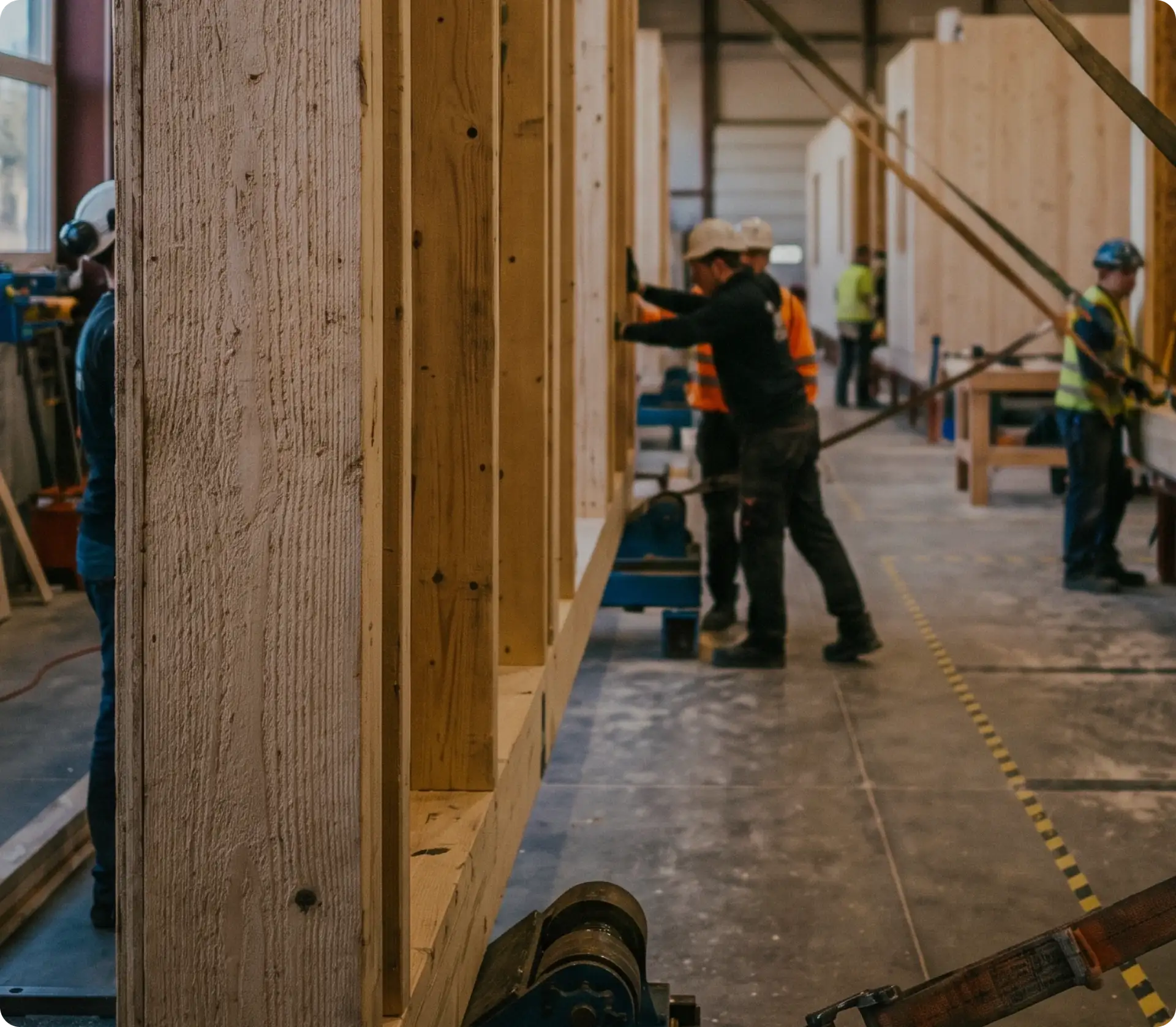 Workers assembling large timber wall panels inside an off-site modular construction facility