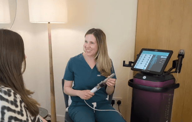 Trish Mueller, founder of Lift and Revive, explaining Morpheus8 V treatment to a female client in the clinic.