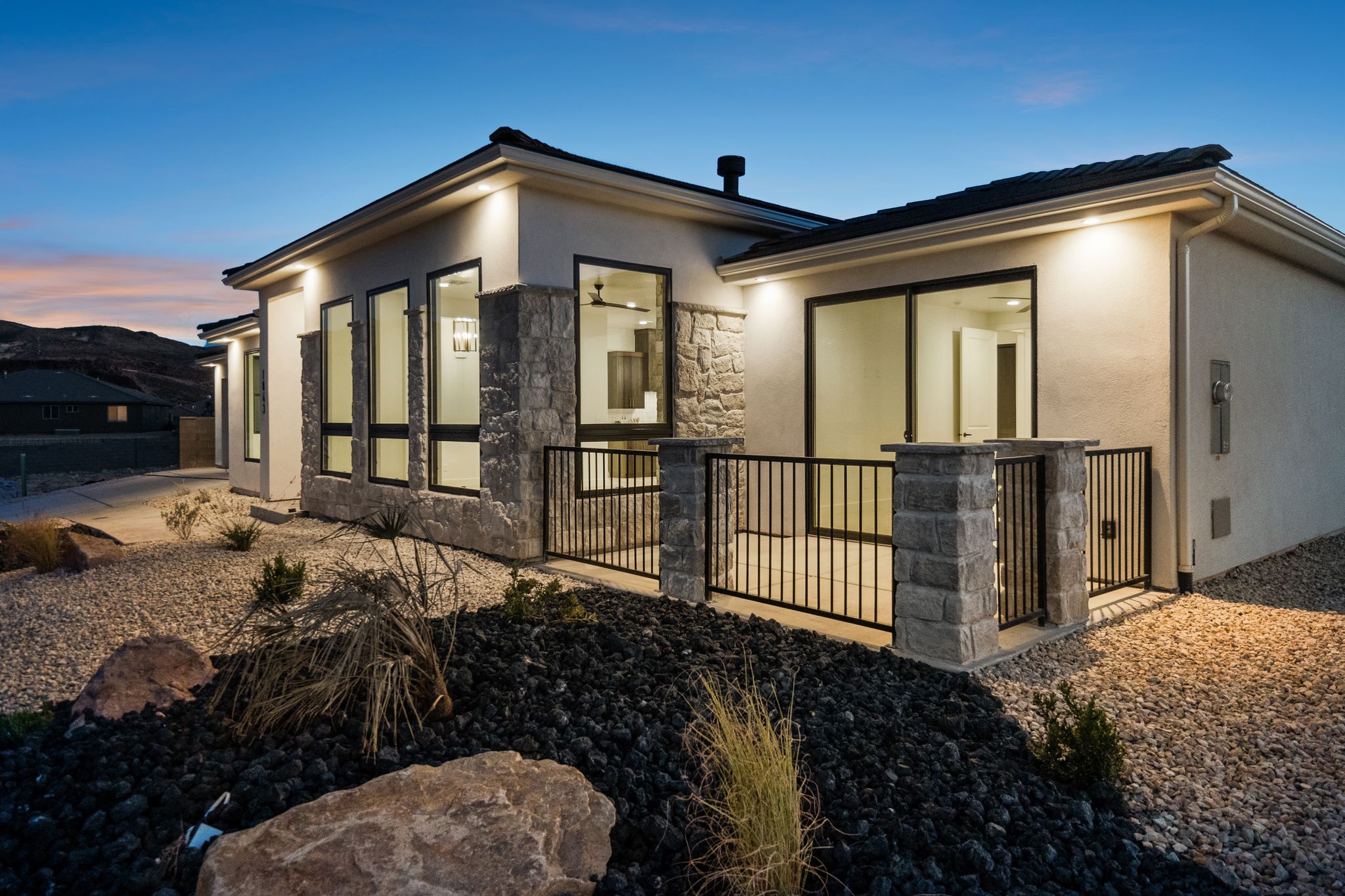 Evening view of The Overlook at Falcon Ridge in Hurricane, Utah, showing illuminated windows and landscaping from the front yard.