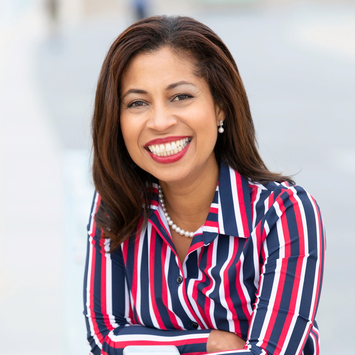 Woman wearing headphones smiles while looking at laptop.