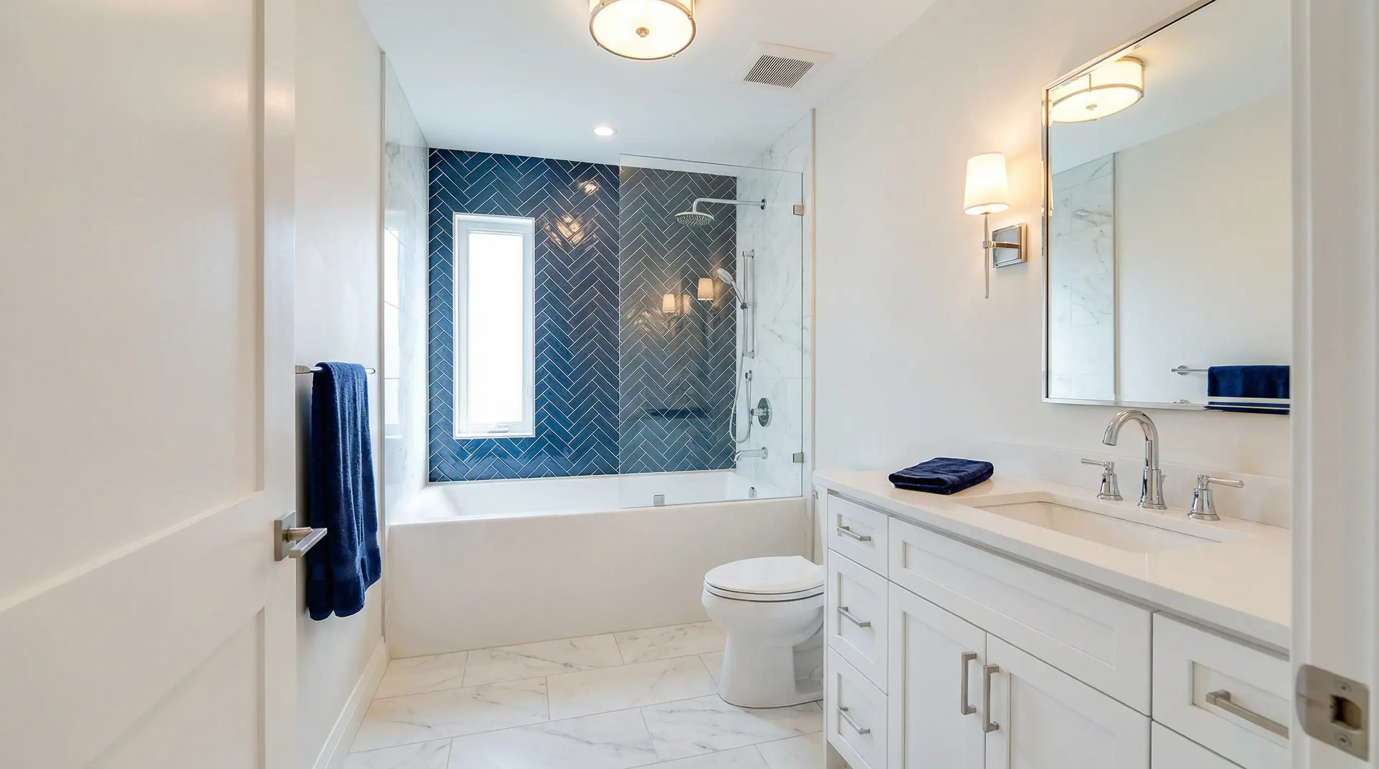 Custom bathroom in Vancouver Custom Homes' West 16th Vancouver multiplex featuring a blue herringbone tile tub-shower combo, frameless glass enclosure, white shaker vanity, and marble tile flooring