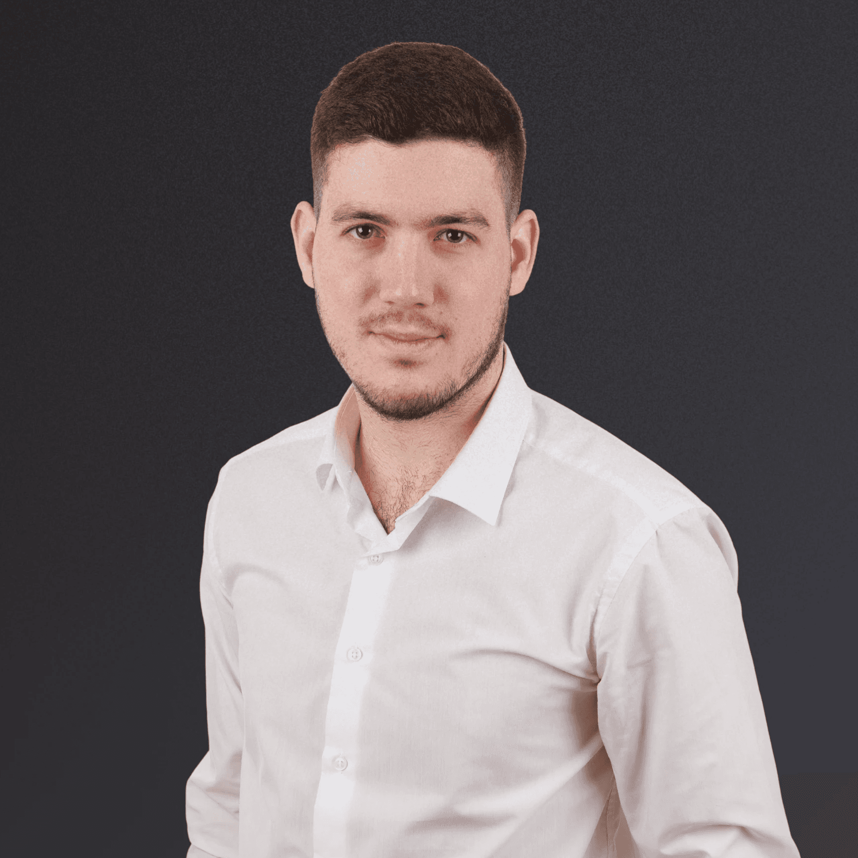 Woman with a short haircut smiling confidently, wearing a blazer and standing in warm natural light with modern architecture behind her.