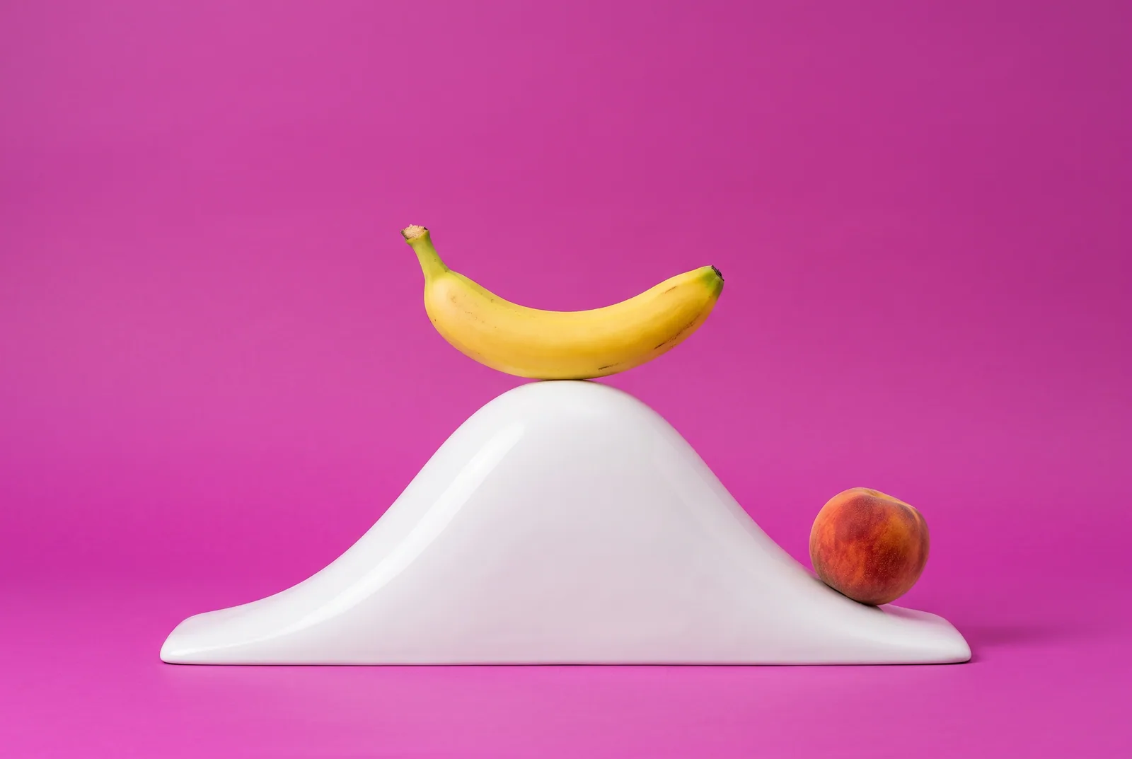 A banana at the peak of a white bell-curve hill and a peach rolling down, how a craving rises and falls in urge surfing