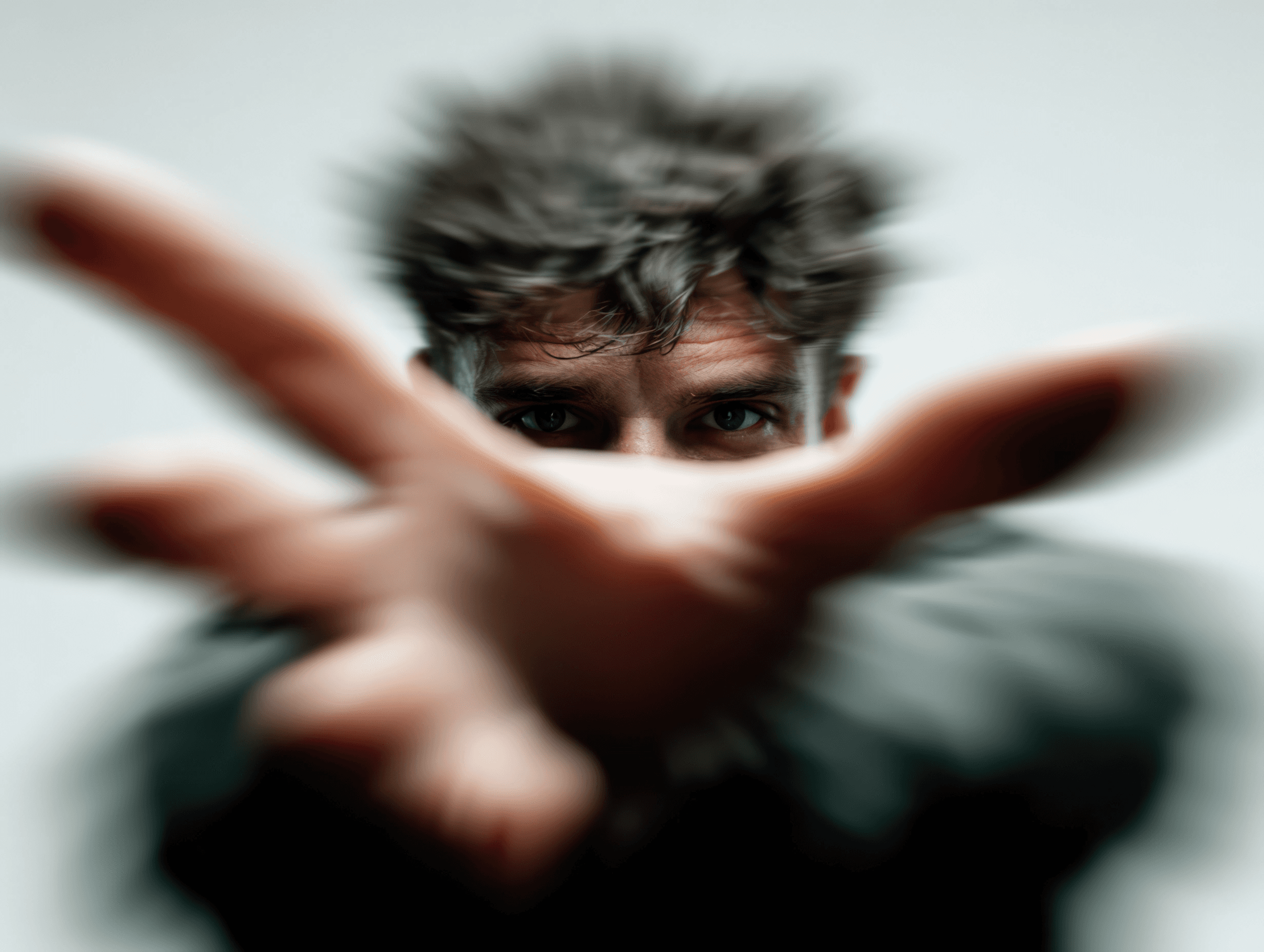 Man reaching toward the camera with outstretched hand, face slightly blurred