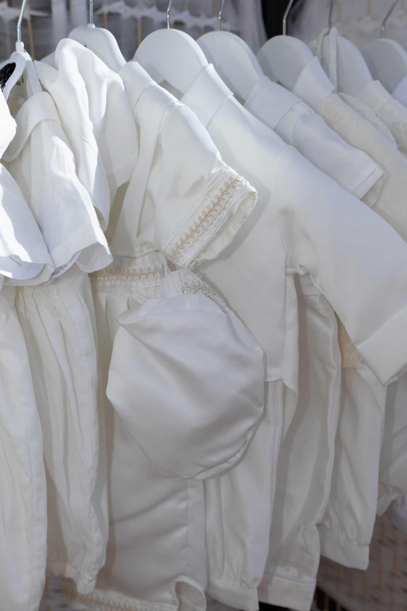 A couple in wedding attire walks hand in hand across a sunlit field.