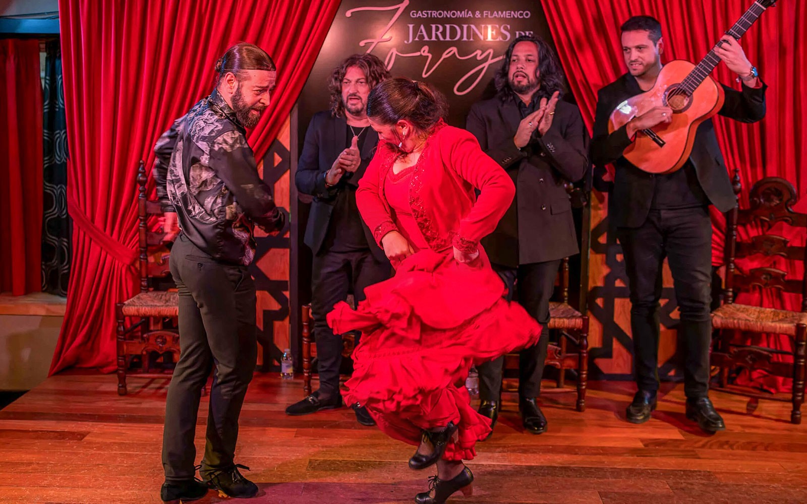 Flamenco dancers performing at Tablao Jardines de Zoraya with musicians in the background.
