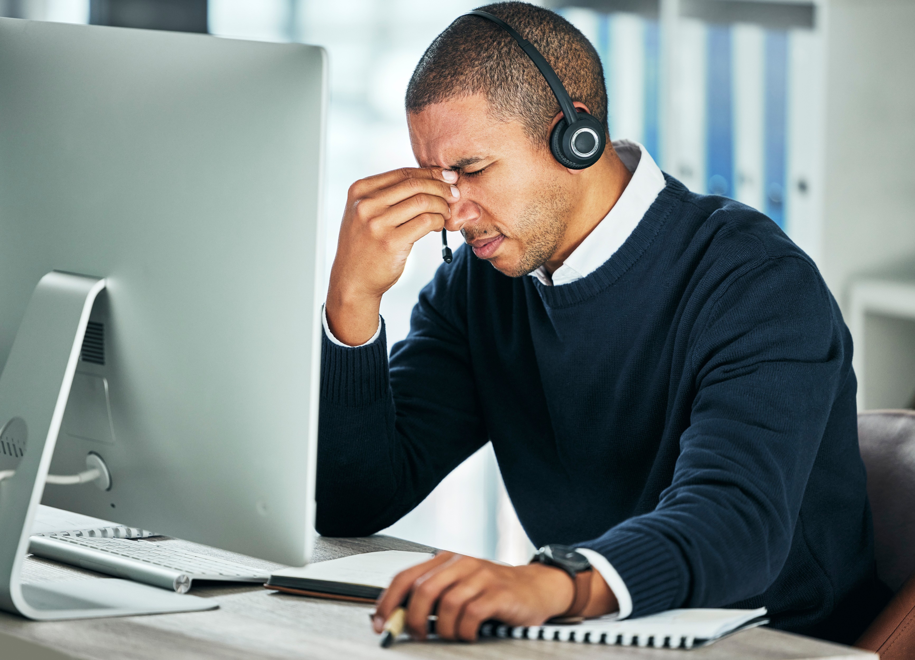 Stressed businessman using a headset, losing VoIP calls to spam flags.