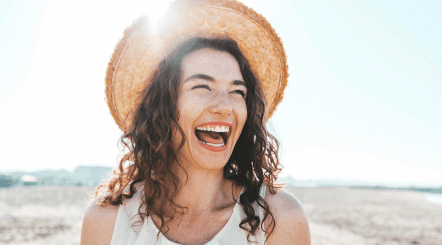 Pregnant woman laughing with man supporting her with his hand on her back and stomach