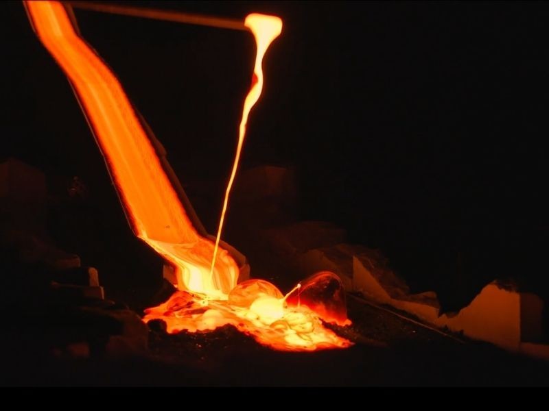 Molten lava being poured indoors at Lava Show, glowing bright orange as it flows and splashes onto a dark surface.