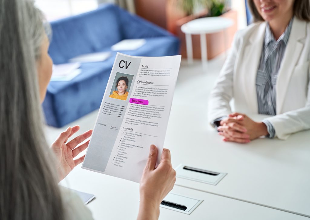 Una recruiter sta intervistando una persona per un posto di lavoro, davanti a sé ha un CV con evidenziata la parola experience.