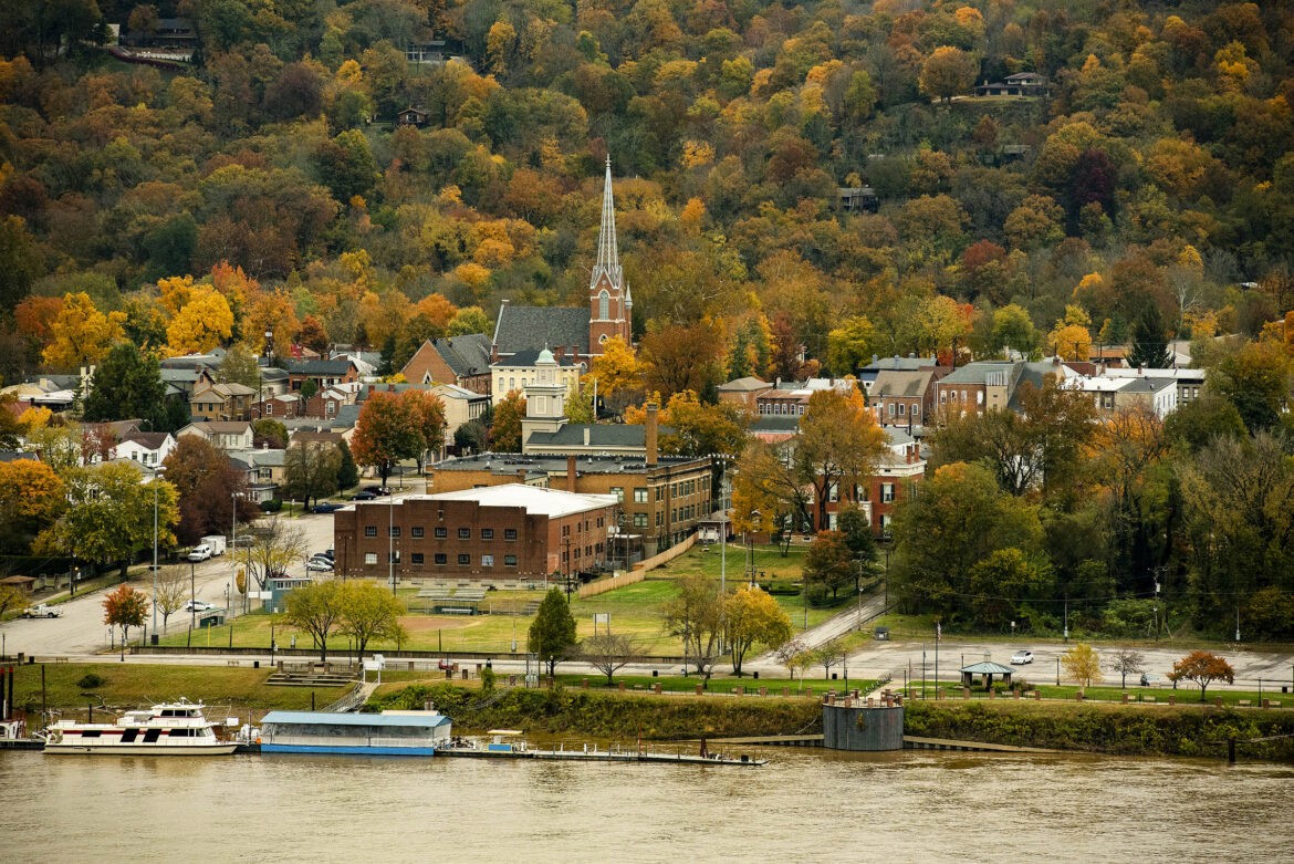 Aerial view of an intersecting dirt pathway forming an X-shape surrounded by lush greenery and arid, rocky terrain, illustrating a contrasting landscape.