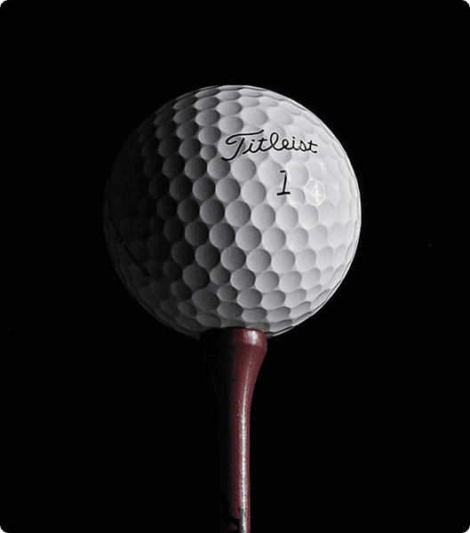 "Close-up of a Titleist golf ball on a red tee against a black background, highlighting the textured dimples and premium branding for golf enthusiasts."
