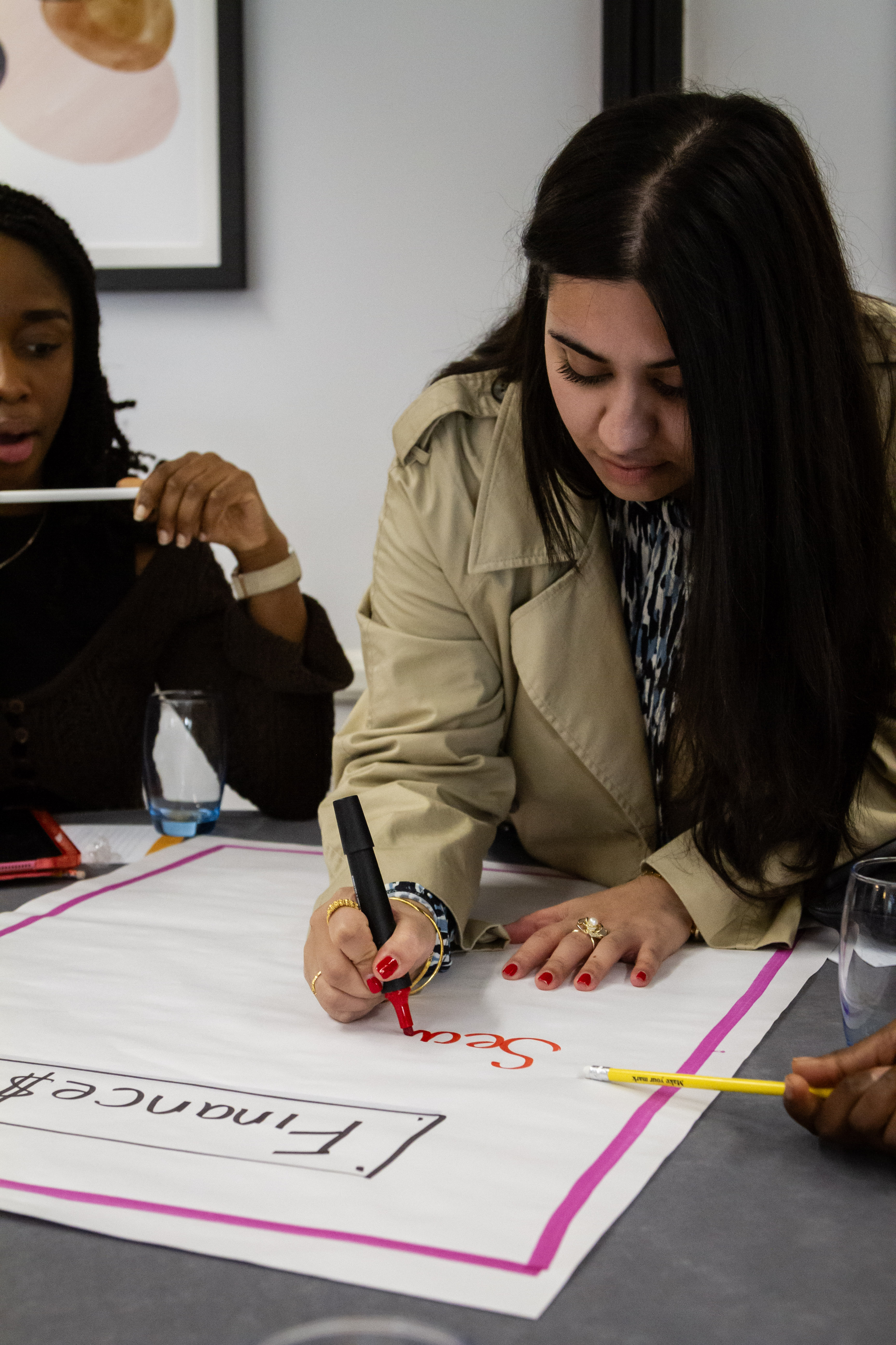 Women writing on flipchart with a red marker pen with women surrounding her. 